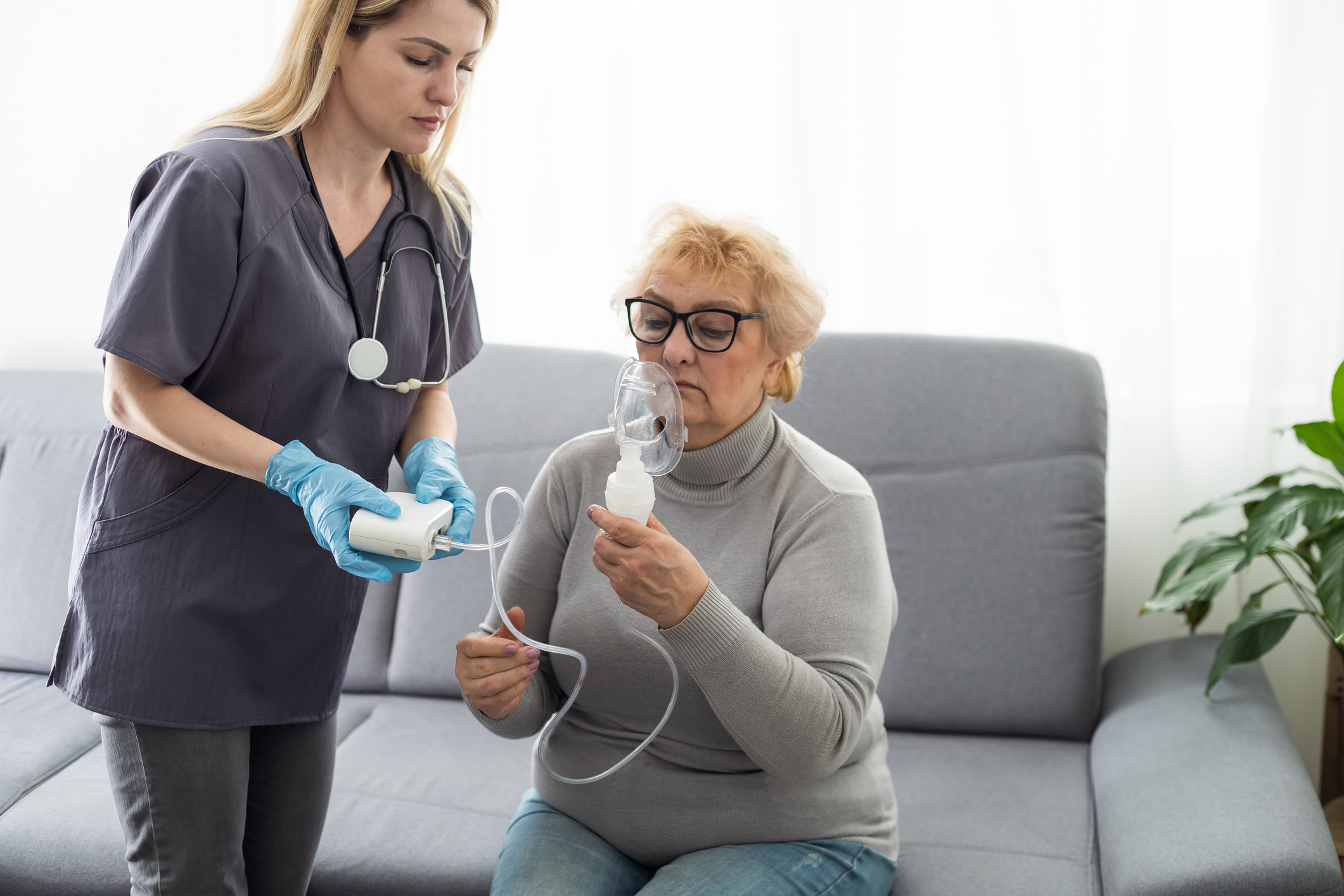Elderly woman using inhaler for asthma and respiratory diseases at home.